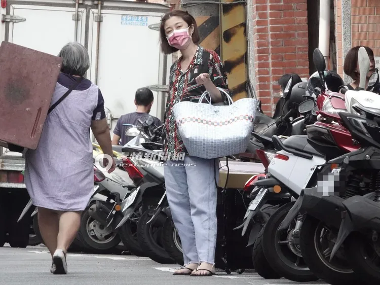 李維維拉著推車，手掛著包包站在街邊等待友人。特勤中心攝