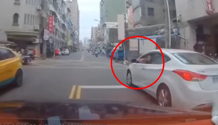 駕駛白色汽車的男子（紅圈處）搖下車窗向對方嗆聲。讀者提供