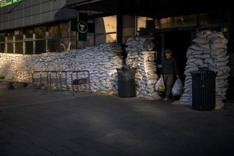 烏克蘭南部造船港市尼古拉耶夫的居民，24日在市中心一家超市購買雜貨。超市外圍堆著大量沙包保護門窗。美聯社