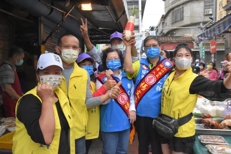 楊文科（右2）走入新埔市場不久，就有熱情鄉親送上蘿蔔，寓意好彩頭。楊文科競辦提供