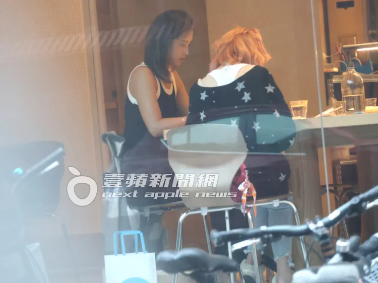 戲劇女神莫允雯（左）穿著運動背心，露出小麥健康膚色的香肩美臂，和身材豐滿的「肉彈妹」邊咖啡邊滑手機。特勤中心攝