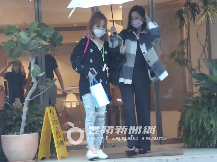 戲劇女神莫允雯（右）撐起小白傘和「肉彈妹」離開咖啡廳。特勤中心攝