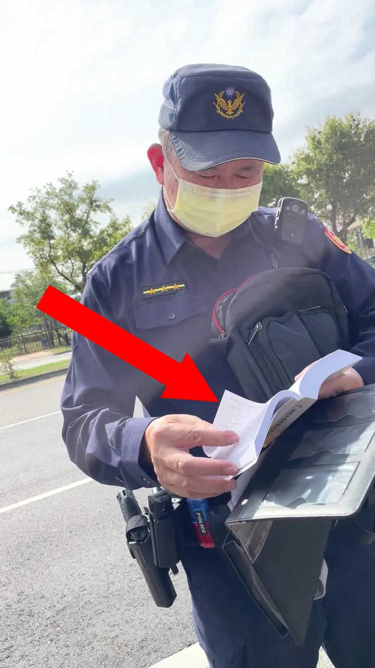 一警當場翻閱法條，時間長約5分鐘，但最終無法找出騎士觸犯哪條違規。 攝自WoWtchout地圖型行車影像分享平台