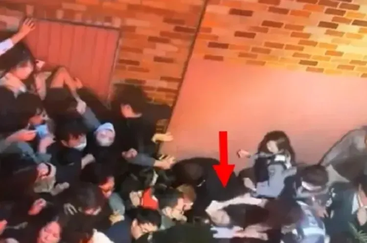 梨泰院死傷者遭人潮堆疊卡死(箭頭處)，右邊大批救難人員正奮力要將她拉出。翻攝宋讚養臉書