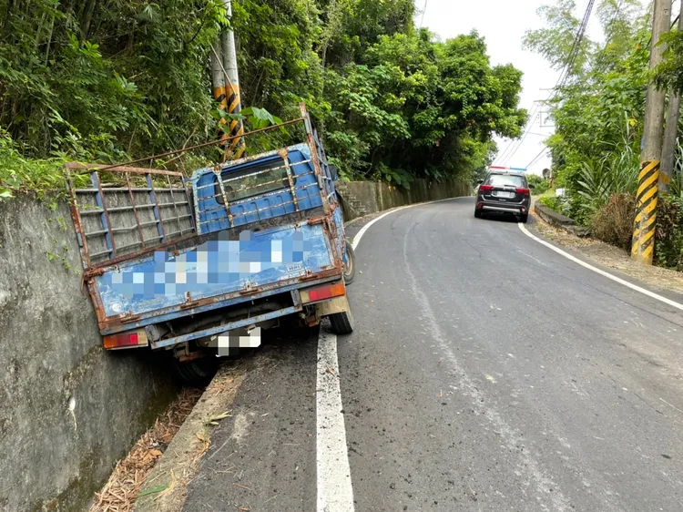 小貨車上坡時疑因來不及換檔而失控下滑，左側車身掉進水溝。讀者提供