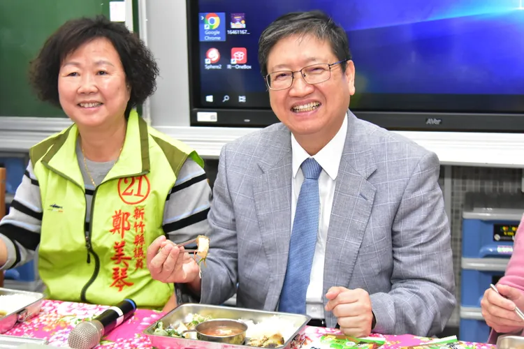 新竹縣長楊文科（右）今和學童共進營養午餐，大啖清蒸石斑魚。新竹縣政府提供