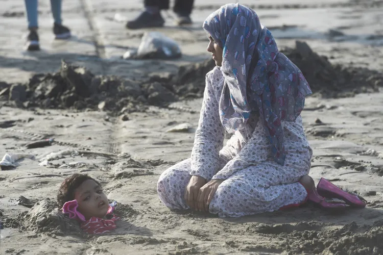 25日下午日偏食期間，這名婦女陪著孩子在喀拉蚩的沙灘上曬太陽。法新社