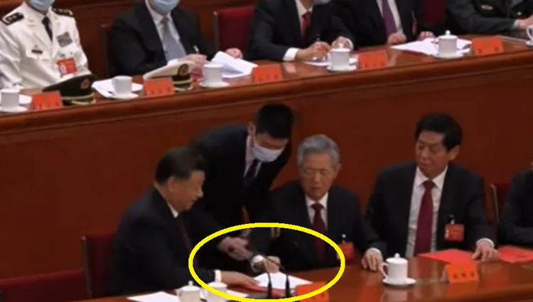 胡錦濤想要拿走習近平面前的文件，習近平壓住文件不讓胡錦濤拿走。法新社