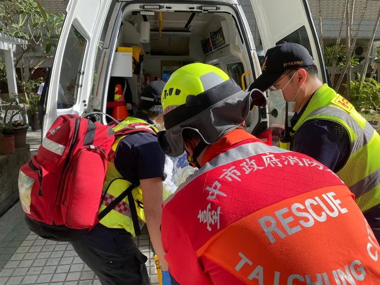 消防隊員將婦人送上救護車。張喆喜攝