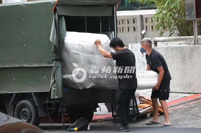 貨車司機及助手，合力將偌大的白色床墊搬下貨車。特勤中心攝