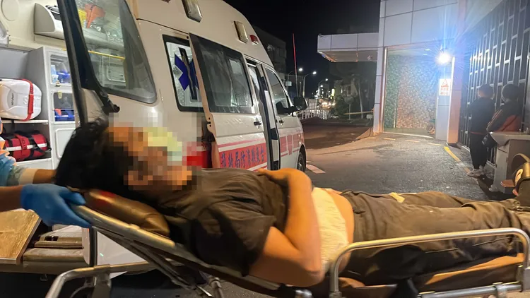 男子神情痛苦的躺在擔架上。古和純攝