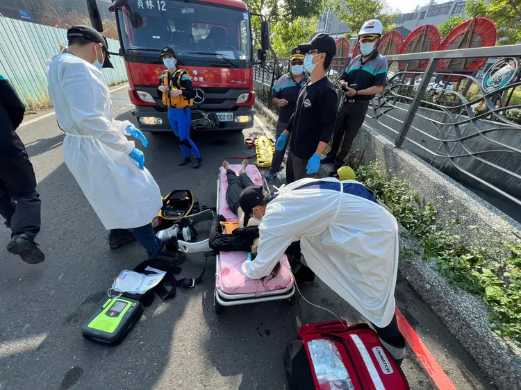 消防員在水圳設置攔截網，將婦人救起送醫。民眾提供