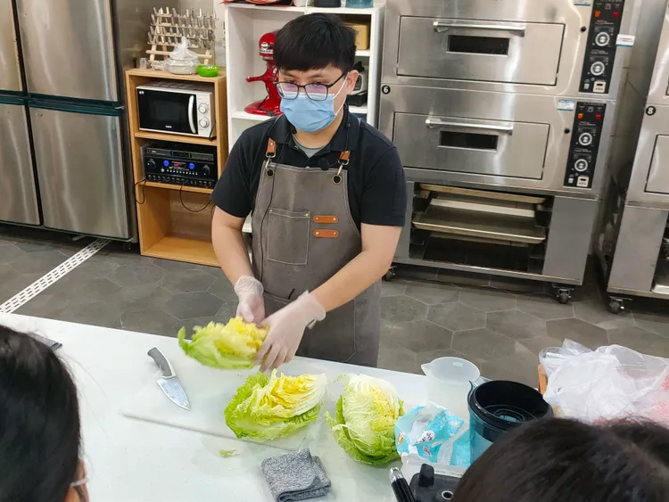 料理達人葉育成現場示範手作泡菜。移民署提供