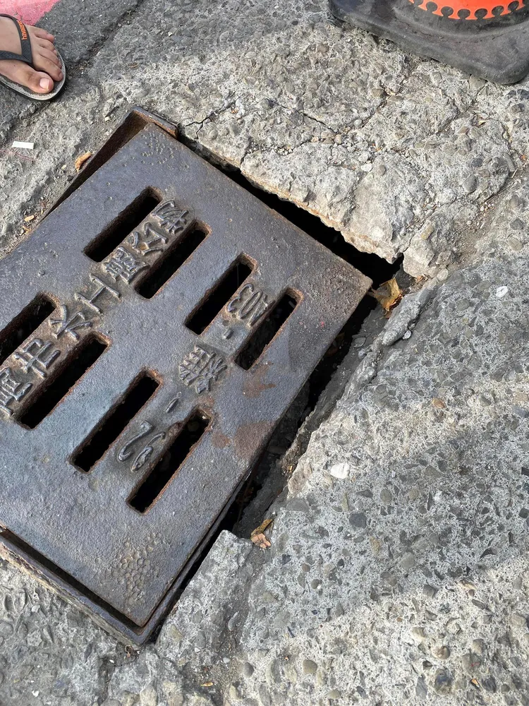 高雄三民區有水溝蓋未固定好，造成行人摔落水溝的意外，被網友形容為「吃人水溝蓋」。翻攝自臉書爆料公社