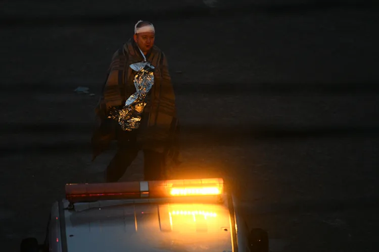 基輔市一名傷者接受簡單包紮後步行途經空襲受災地點。美聯社