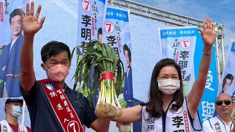李佳芬(右)贈大蒜給弟弟李明哲，象徵「凍蒜」預祝順利當選。魏嘉良攝
