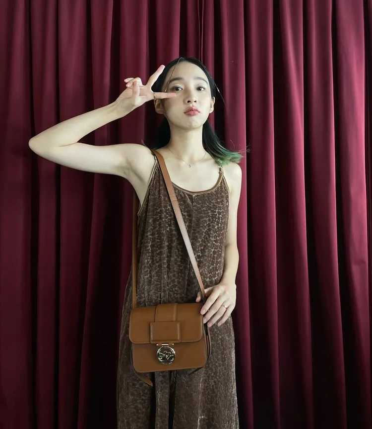 女星李沐日前進行拍攝時，身穿褐色背心洋裝搭配Box-Trot系列經典白蘭地酒色小型斜背包展現甜美樣貌。翻攝mumoonlee IG
