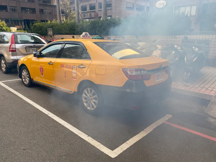 濃煙從計程車底盤不斷竄出。張喆喜攝