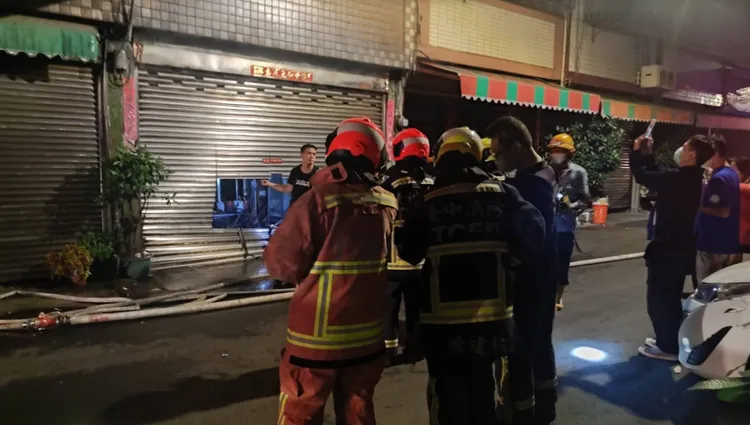 現場為4樓建築。頂樓鐵皮加蓋，消防隊員切割1樓鐵捲門搶救。讀者提供