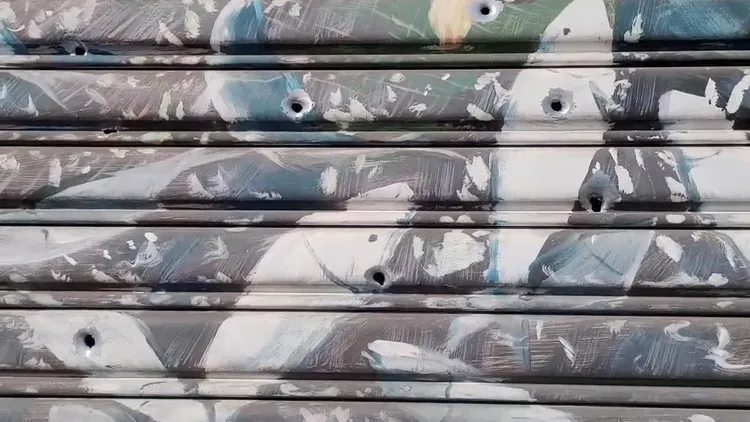 鐵捲門上有多處彈孔。劉榮輝攝