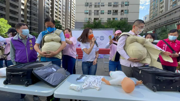 張善政(左)和謝國樑打扮成孕婦幫嬰兒包尿布和著裝。張沛森攝