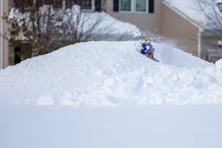 一名男子19日在與深及一人高的雪堆之中鏟雪。路透社
