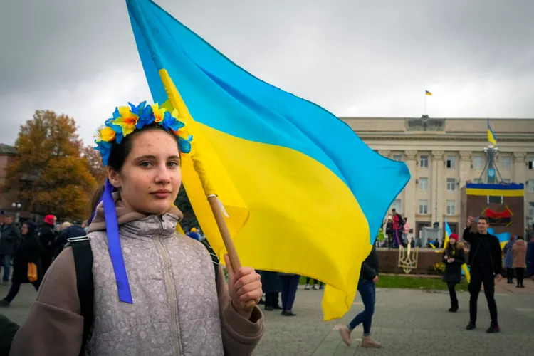 赫爾松市一名少女13日頭帶傳統花冠、手握烏克蘭國旗，在赫爾松市中心參加慶祝光復活動。美聯社