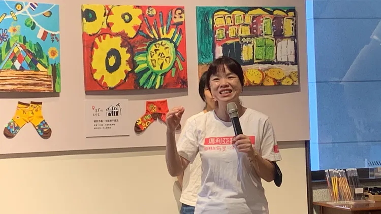 瑪利亞社福基金會藝術老師說明學員們走進中區邊讀邊學邊繪畫身後展出創作的過程。曾雪蒨攝