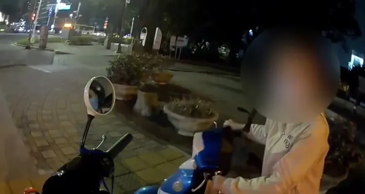 越籍女子牽著電動機車跟警員前往派出所。讀者提供