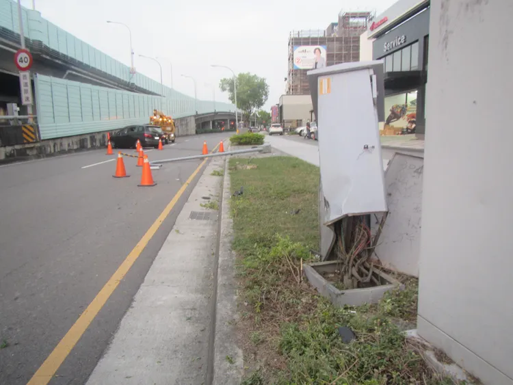 事故現場路燈箱傾倒，燈桿橫倒佔據車道，肇事自小客也打橫柱上匝道水泥護欄。讀者提供