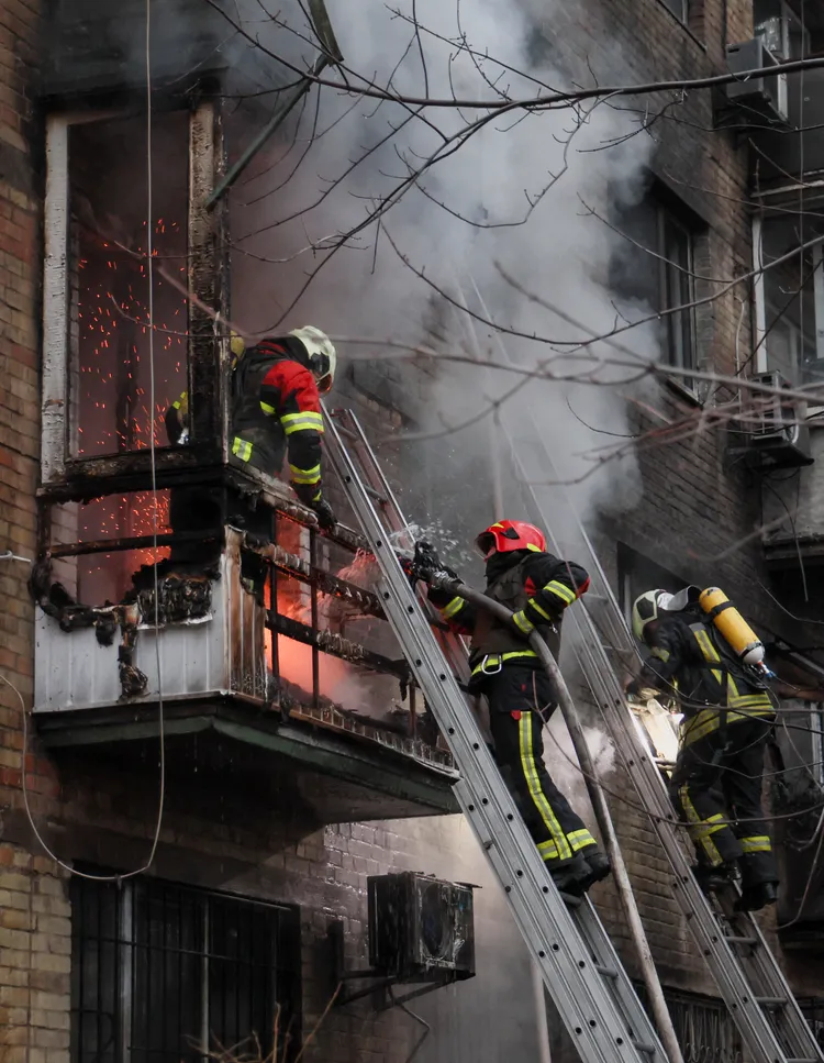 烏克蘭首都基輔消防隊員15日在一處遭俄軍飛彈擊中的公寓救援受困民眾。路透社