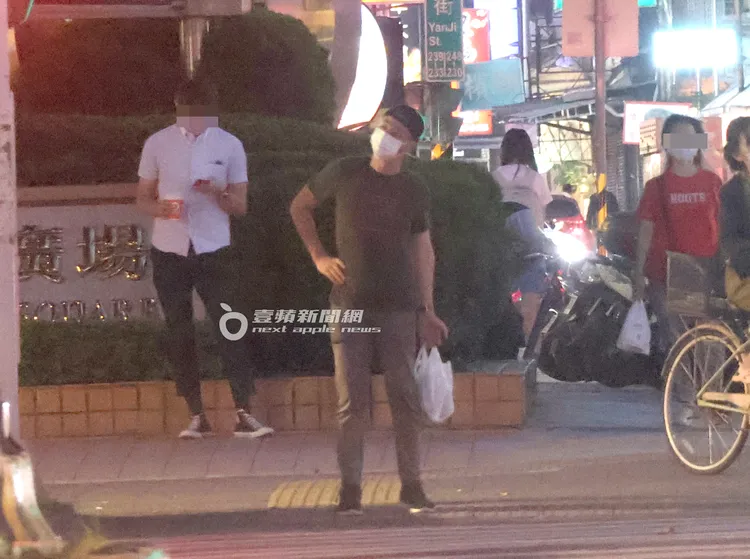 霍建華提著一袋「戰利品」，等紅綠燈過馬路，邊做伸展操運動、活絡筋骨。特勤中心攝