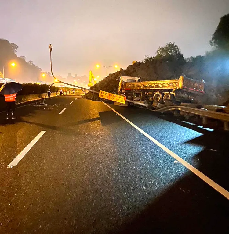 大量土石滑落到路面，險些壓到路旁的砂石車，連告示牌都被壓到歪曲變形。翻攝畫面