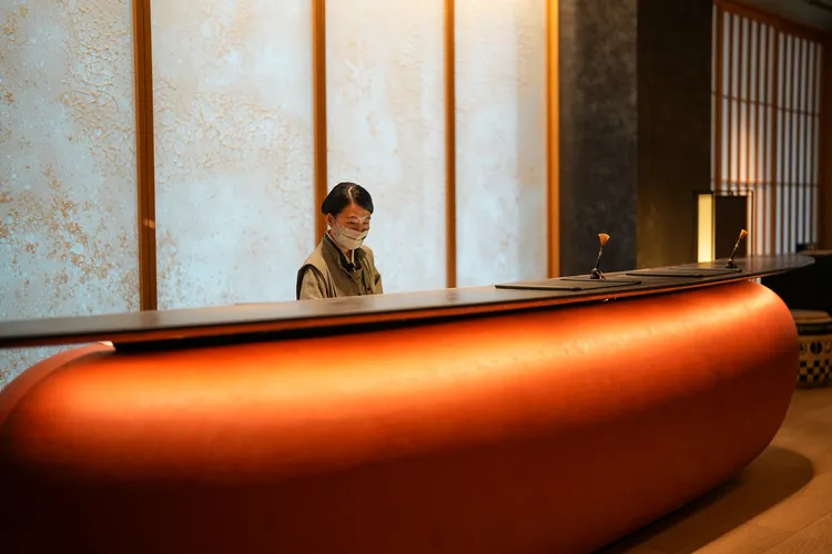 虹夕諾雅 東京的接待大廳(reception)以寺廟的大堂作為設計靈感來源。櫃台融合了代表「和」（和風）的形狀以及顏色。有點像日本武士的盔甲，又有點像和菓子, 櫃台後方還使用了「和紙」設計，希望旅客可從中感受到日本的元素。田欣雲攝