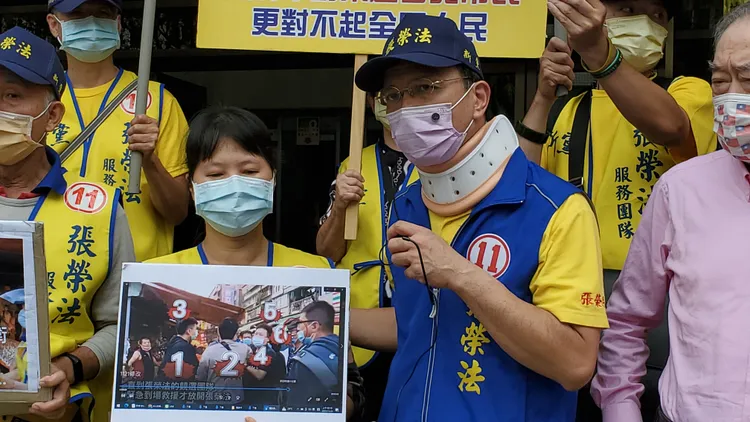 張榮法指著妻子手上拿的照片說當時他被這群人圍住施暴。呂志明攝