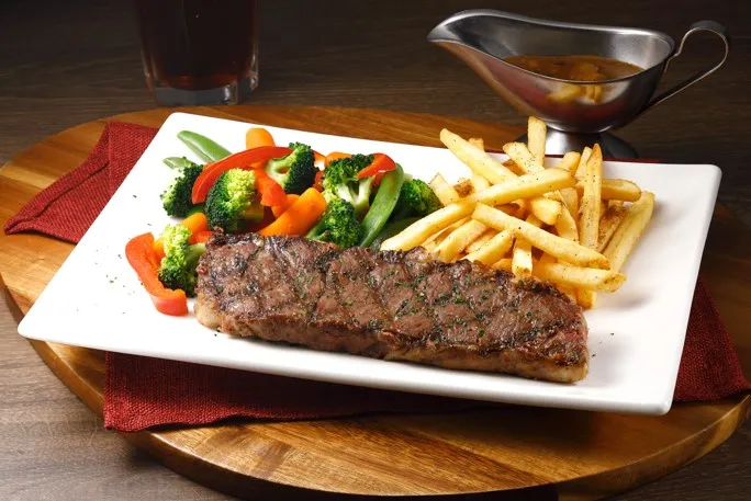TGI FRIDAYS精選8 oz.美國沙朗牛排，搭配配菜薯條及季節時蔬一同享用。業者提供