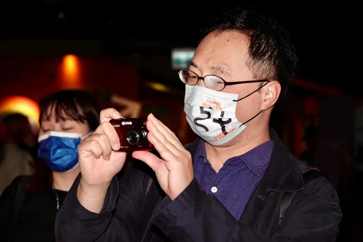 深田晃司眼鏡起霧，但看到自己的電影海報仍拿起相機拍照留戀。陳德興攝