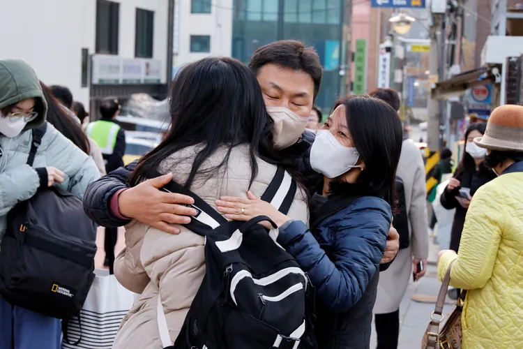 南韓考生家長送孩子到考場門口，依依不捨擁抱打氣。路透社