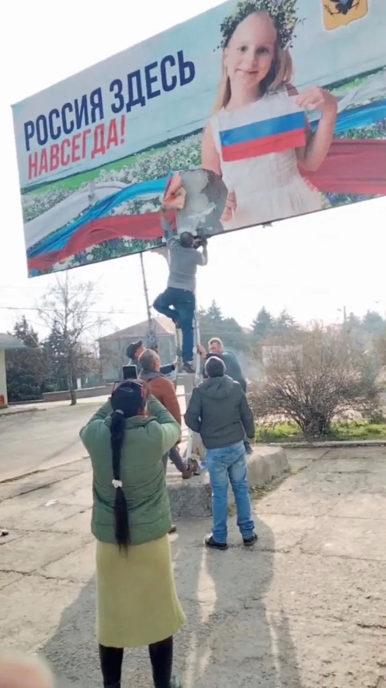 俄軍撤走後，烏克蘭民眾扯掉赫爾松市中心的俄國宣傳布條。路透社