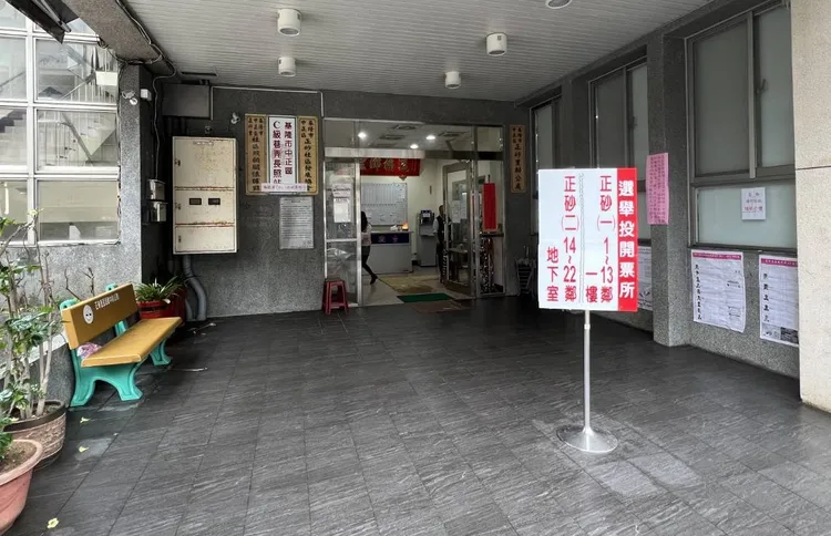 女子在正砂里民活動中心外比手勢，經選委會認定違規。翻攝畫面