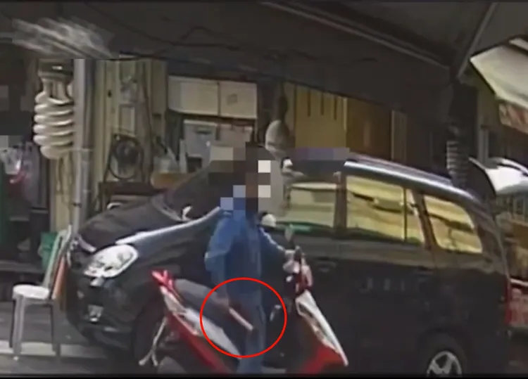 林男從機車前置物箱中取出鐵錘。讀者提供