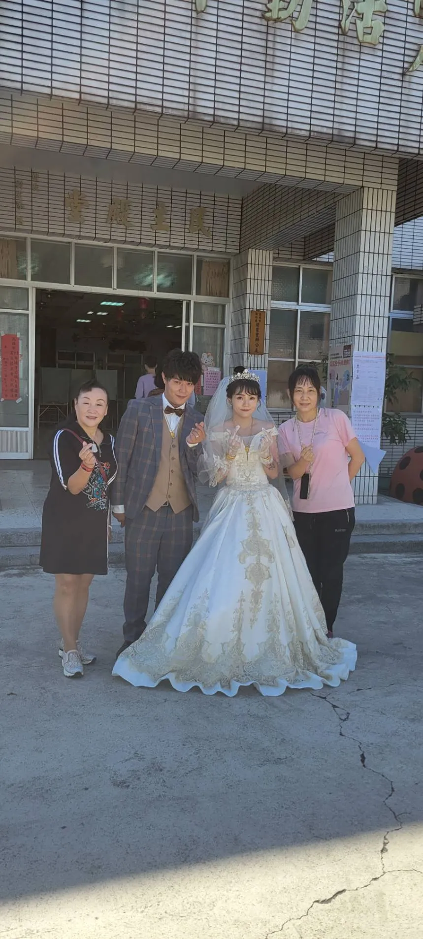 選務人員與媒人婆賴秀紅(左1)特地與新人在投開票所前合照留念。讀者提供