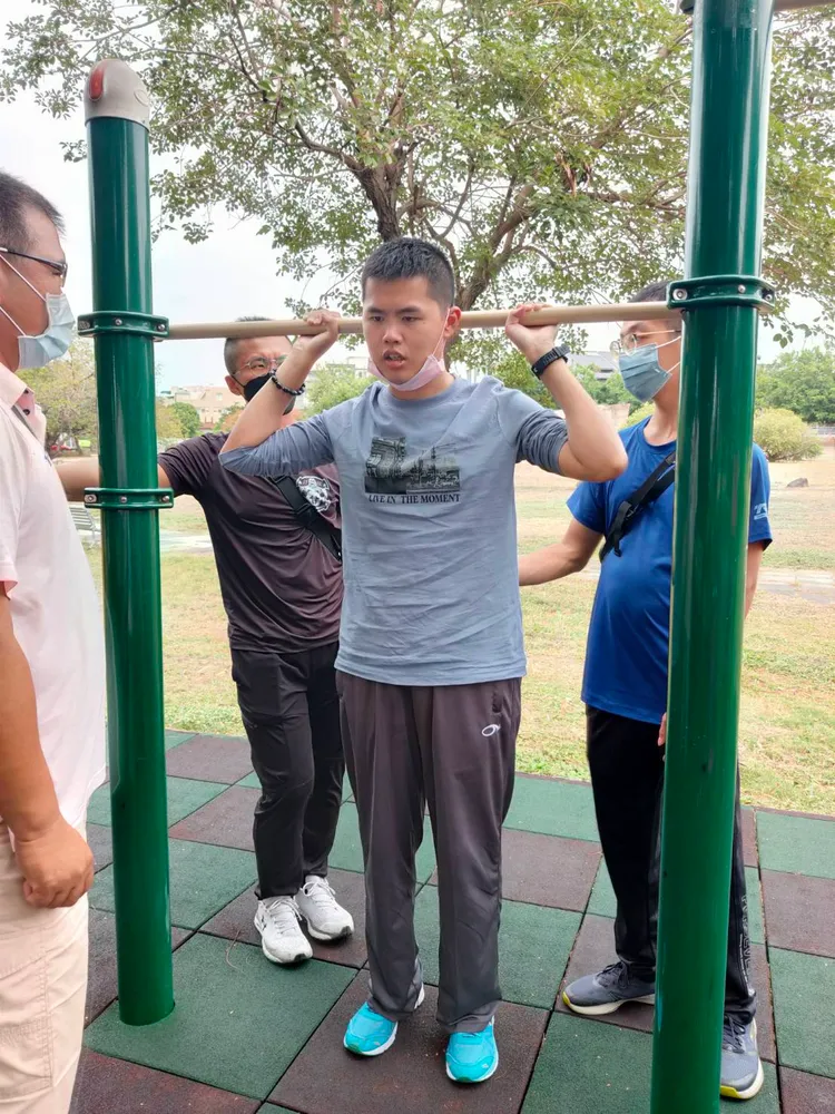 秦良丰在衛武營公園試著舉手拉住單槓。秦爸爸提供