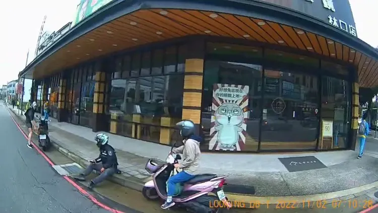 路人幫騎士將機車扶起，騎士則坐在路旁休息。翻攝自臉書社團「林口大家庭LinKou-Family」