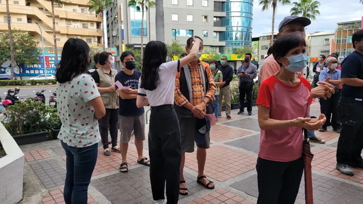 選務人員為民眾噴酒精量額溫。劉榮輝攝