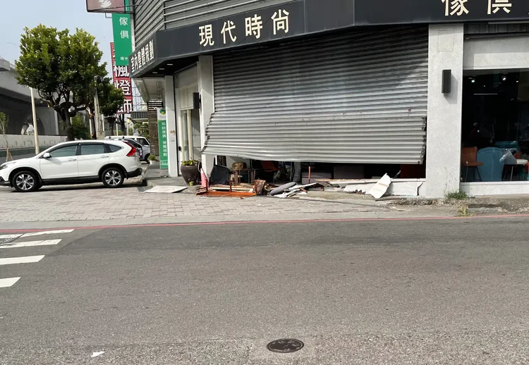 傢俱行鐵捲門扭曲變形，門下散落傢俱殘骸。王煌忠攝