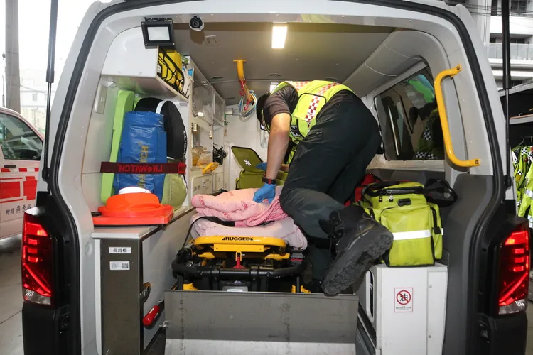 消防局救護人員將墜樓婦人送醫。示意圖