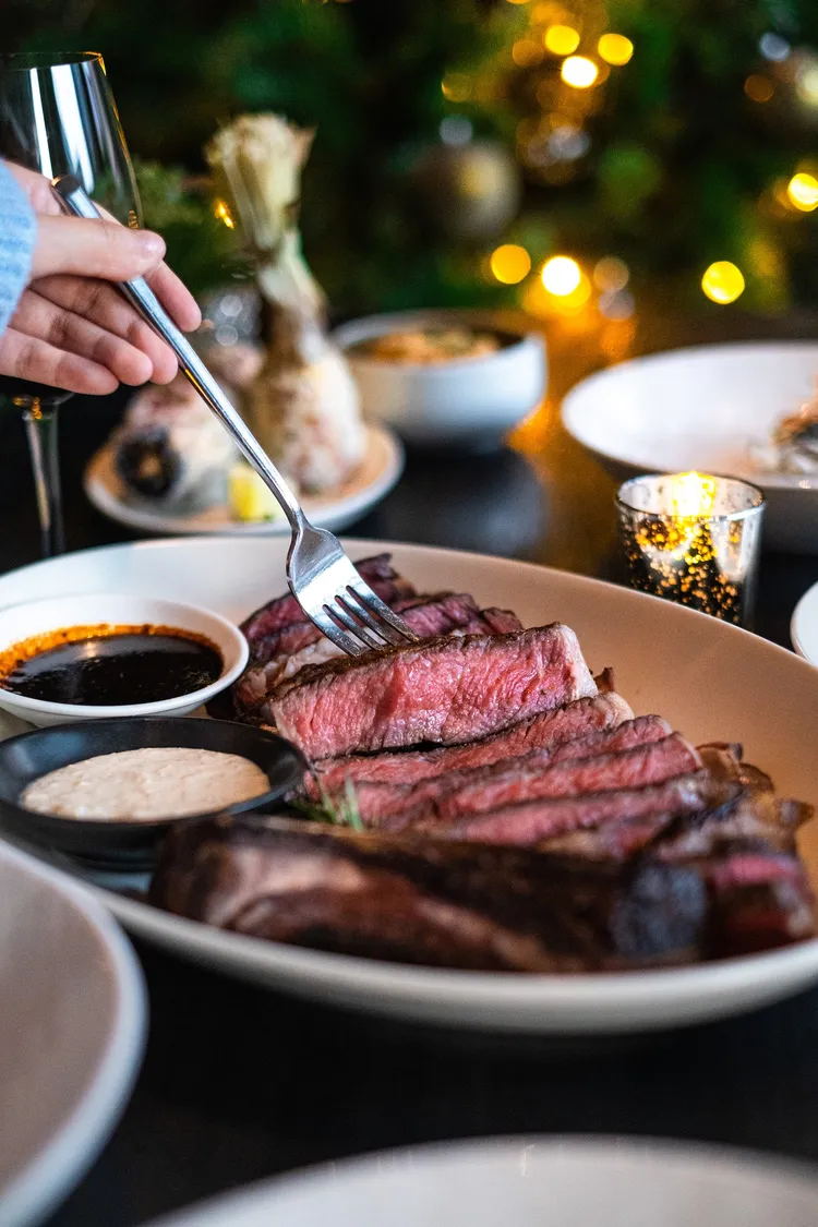 雙人美國頂級乾式熟成28日帶骨肋眼牛排的切面紅嫩，富有豐沛的香甜肉汁。業者提供