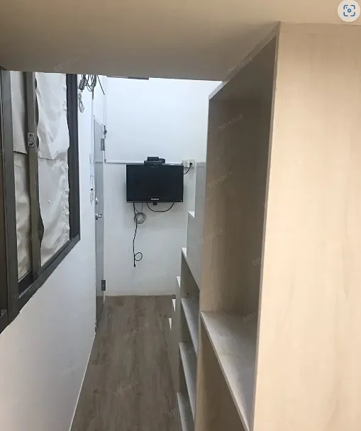 套房窄道後方牆面其實還有安裝電視，並非只擺放一張桌子和床鋪。翻攝591房屋交易