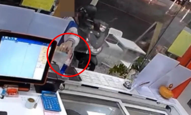 王姓男子伸手偷走店家的捐款箱（紅圈處）。讀者提供